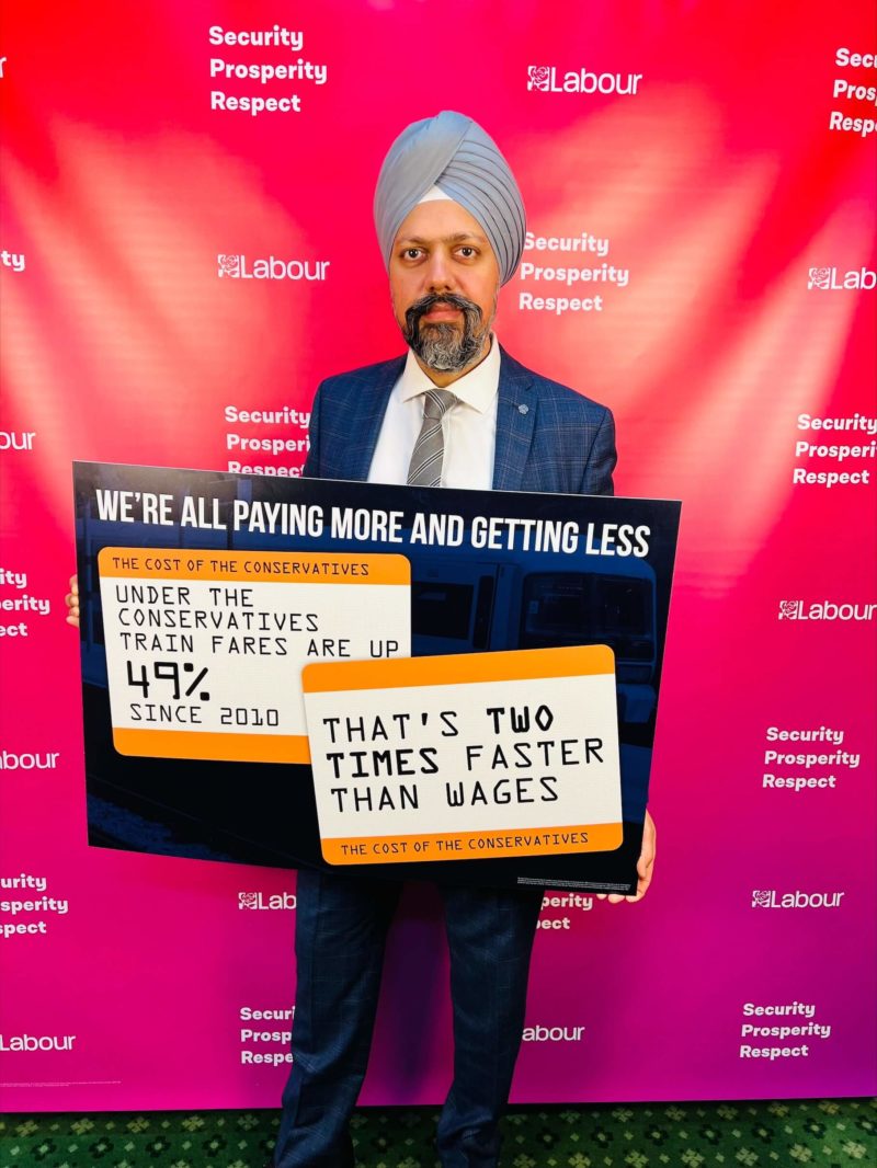 Tan Dhesi holding sign on rail fares under Tories