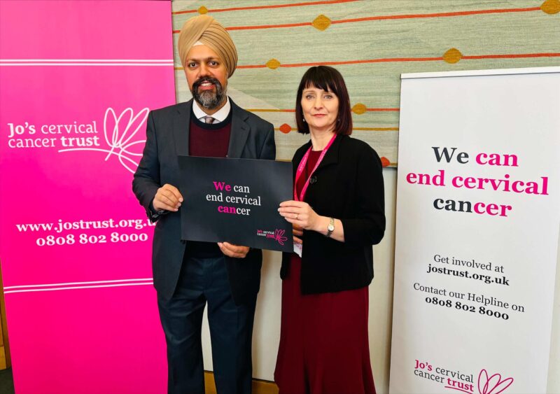 Tan Dhesi holding a sign which reads: "We can end cervical cancer."