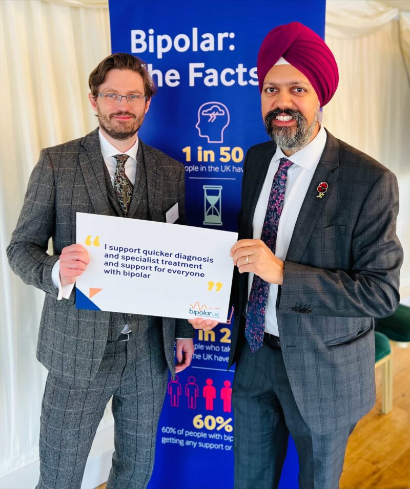 Tan Dhesi holding a sign calling for quicker diagnosis and support for people with bipolar.